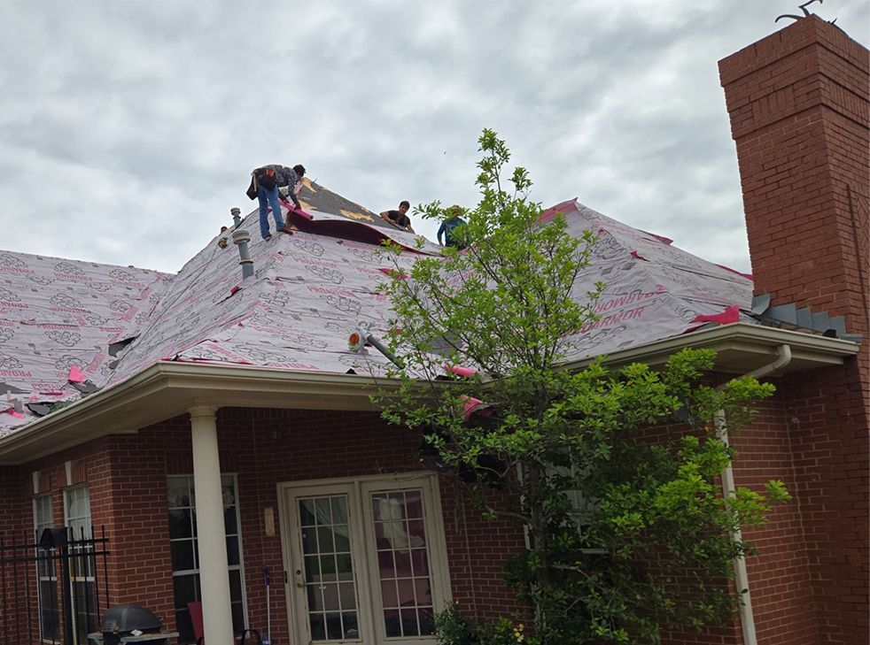 A group of people are working on the roof of a brick house.