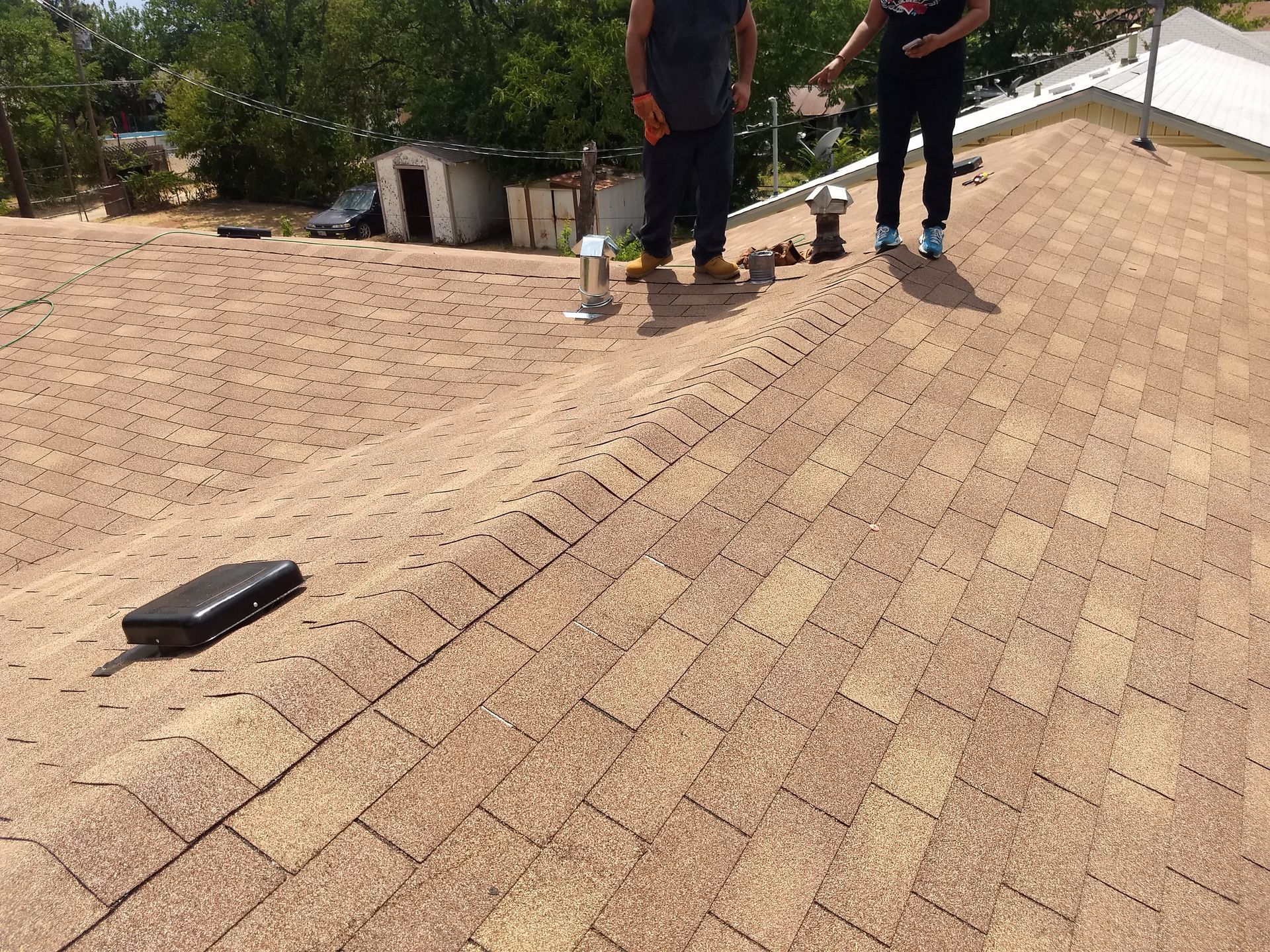 Two men are standing on top of a roof.
