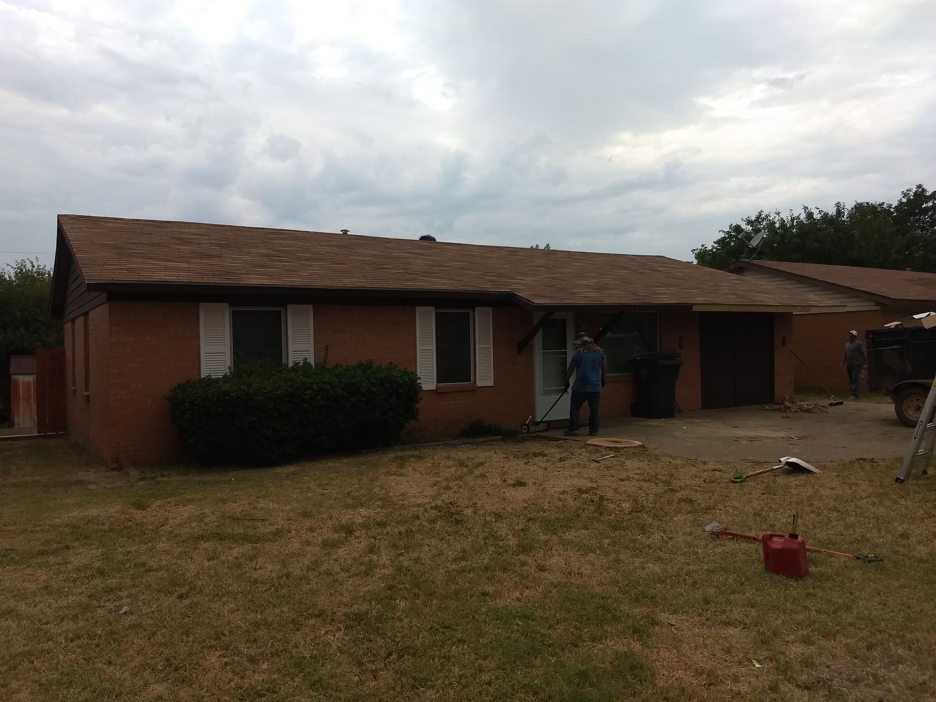 A man is standing in front of a brick house