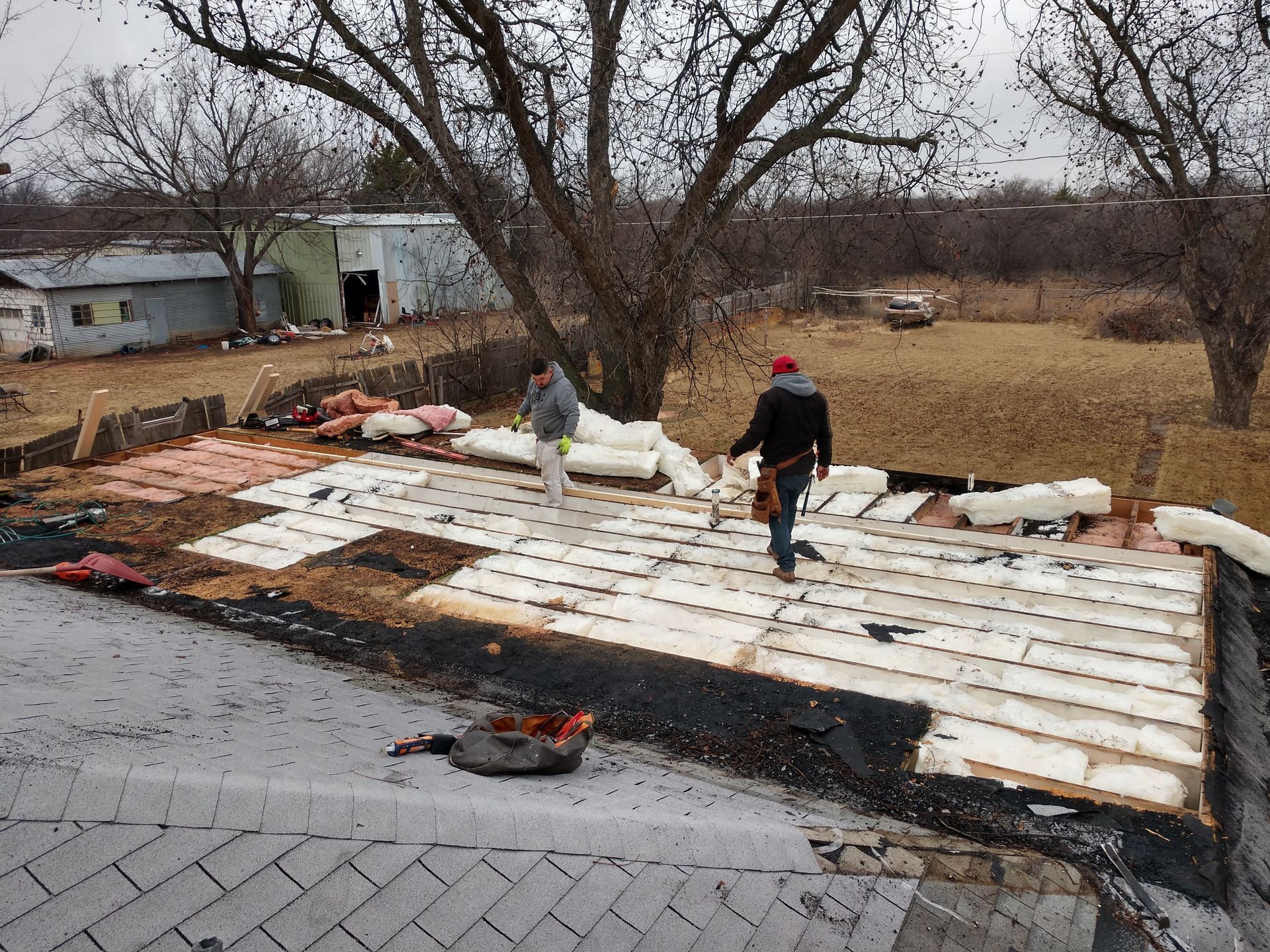 Two men are working on the roof of a house
