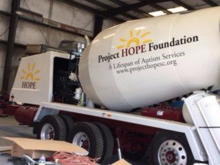 A concrete mixer truck from the project hope foundation is parked in a garage.