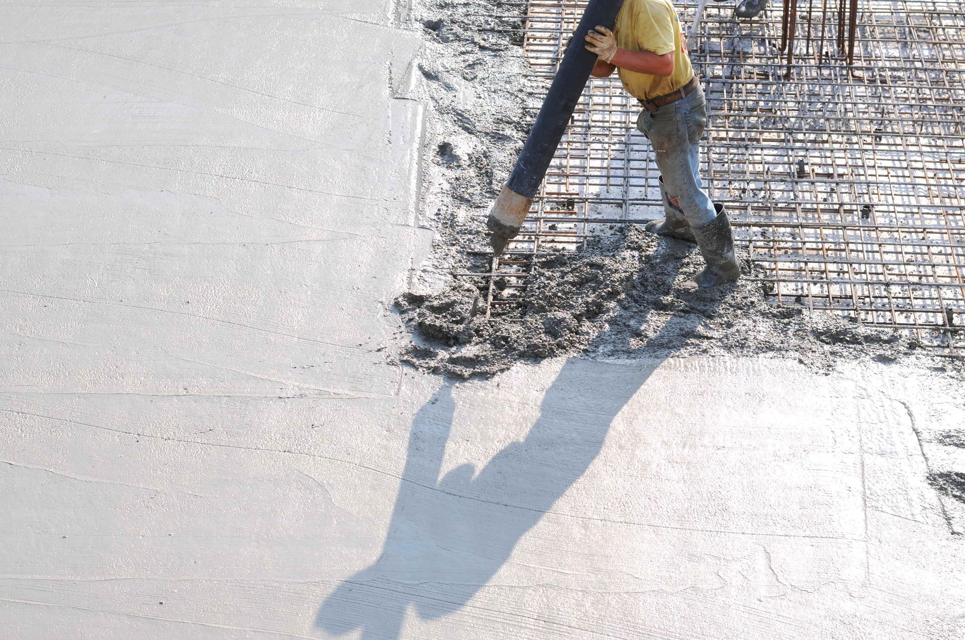 A man is pouring concrete into a grid with a hose.