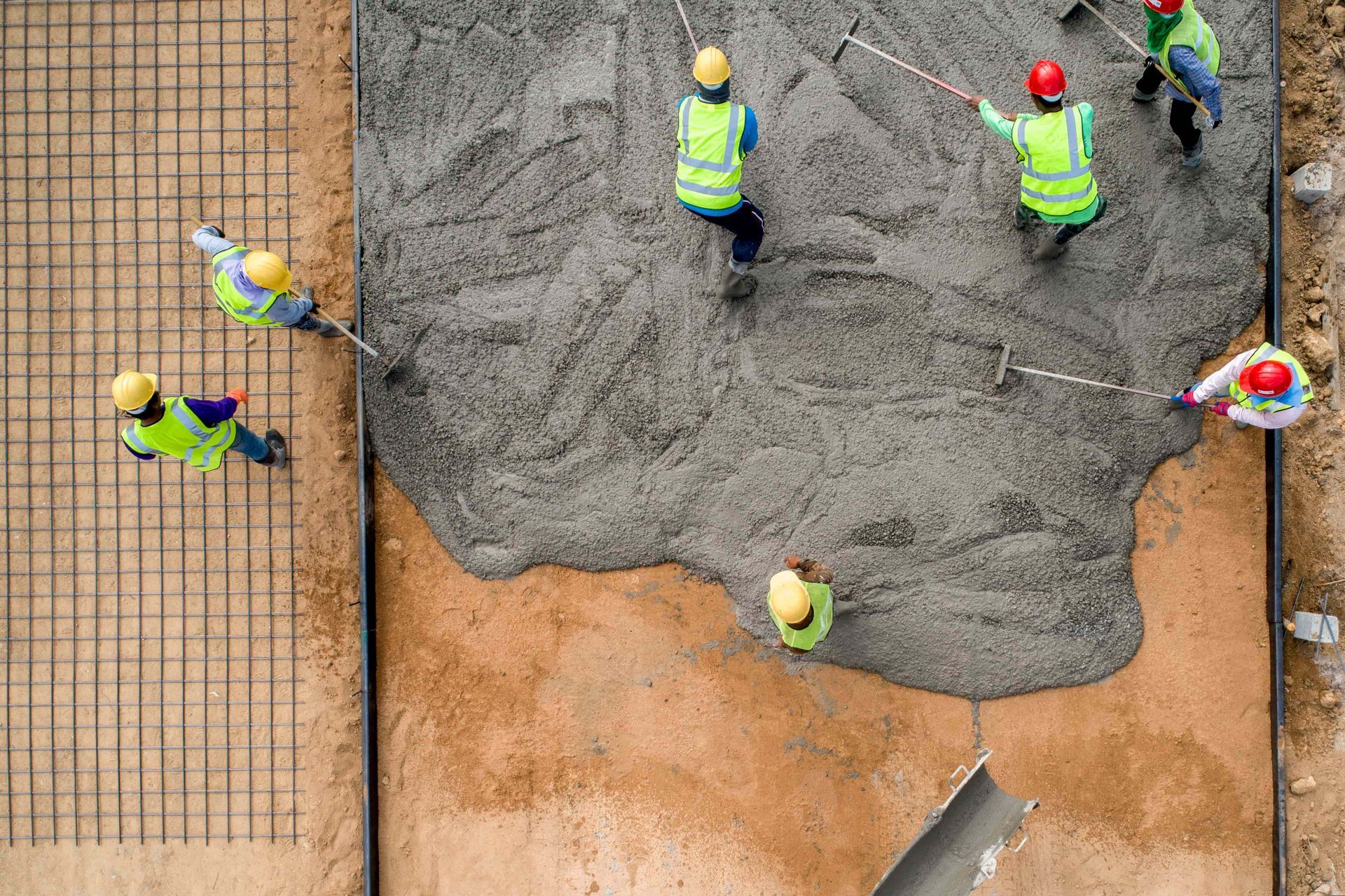 A group of construction workers are pouring concrete on a construction site.