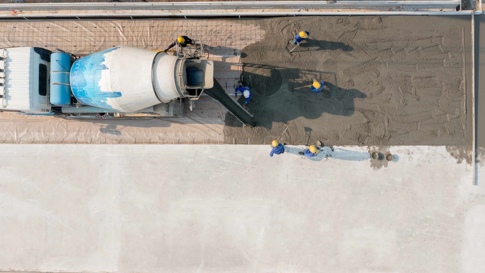 A man is pouring concrete into a grid with a hose.