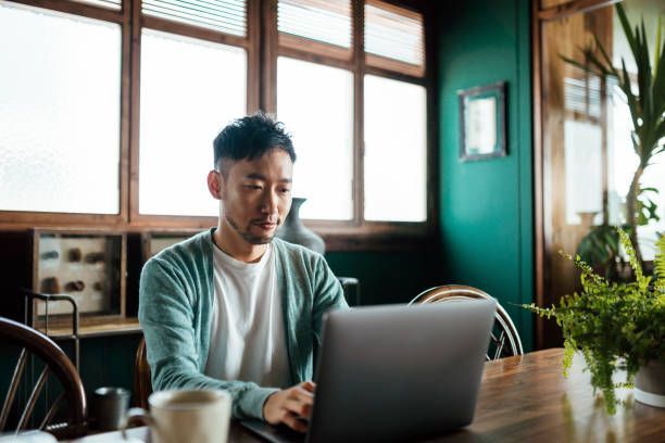 A man is sitting at a table using a laptop computer.