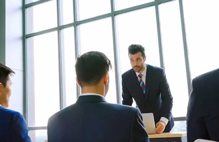 A man in a suit and tie is giving a speech to a group of people.