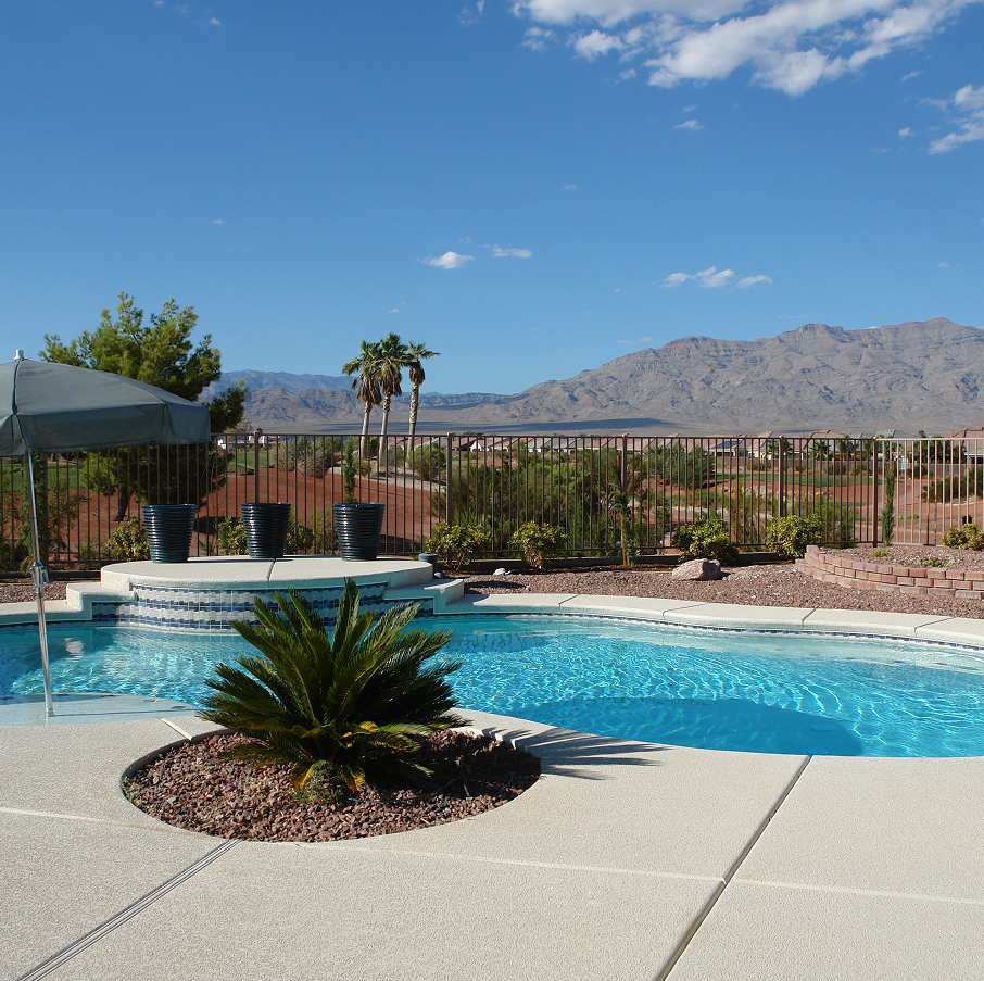 Swimming pool with mountains in the background under a blue sky.