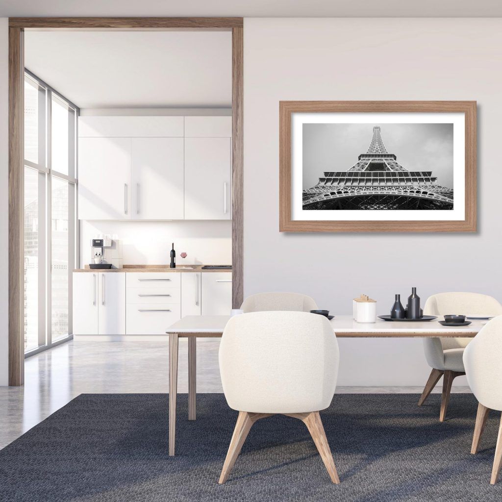Una foto della Torre Eiffel è appesa sopra un tavolo da pranzo e delle sedie