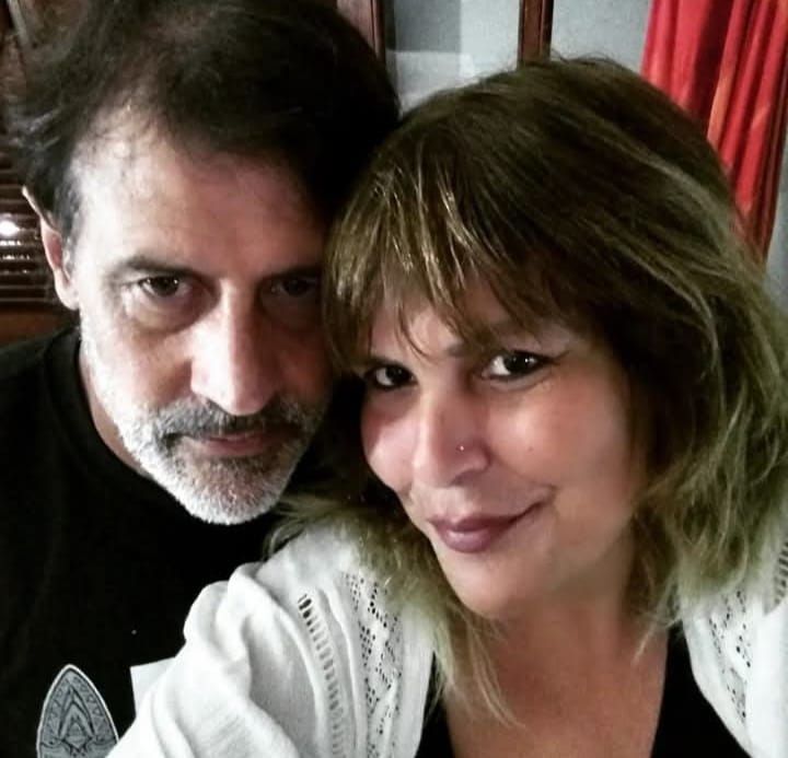 Hombre y mujer sonriendo, primer plano. Cabello oscuro, piel clara, ambiente acogedor.