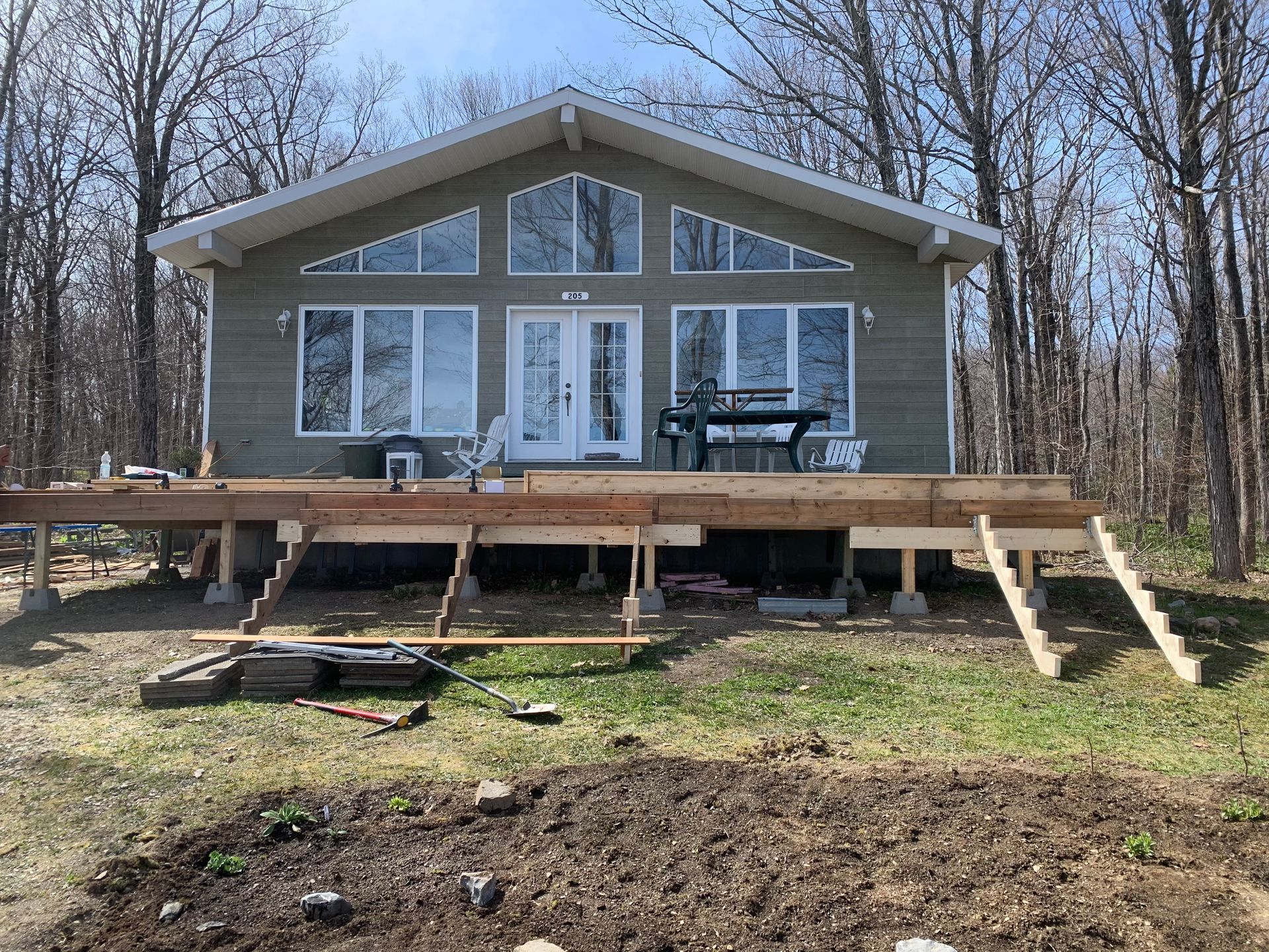 Une maison avec une terrasse en bois est en construction dans les bois.