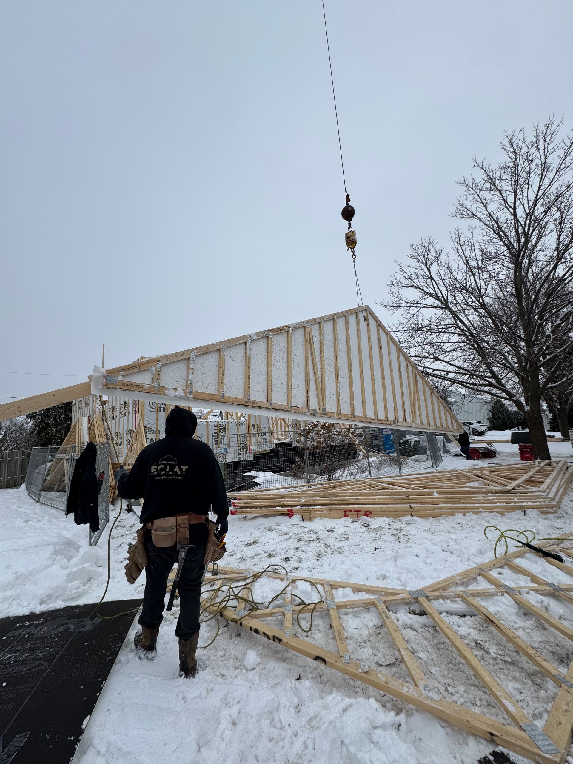 Un homme marche dans la neige devant un bâtiment en construction.