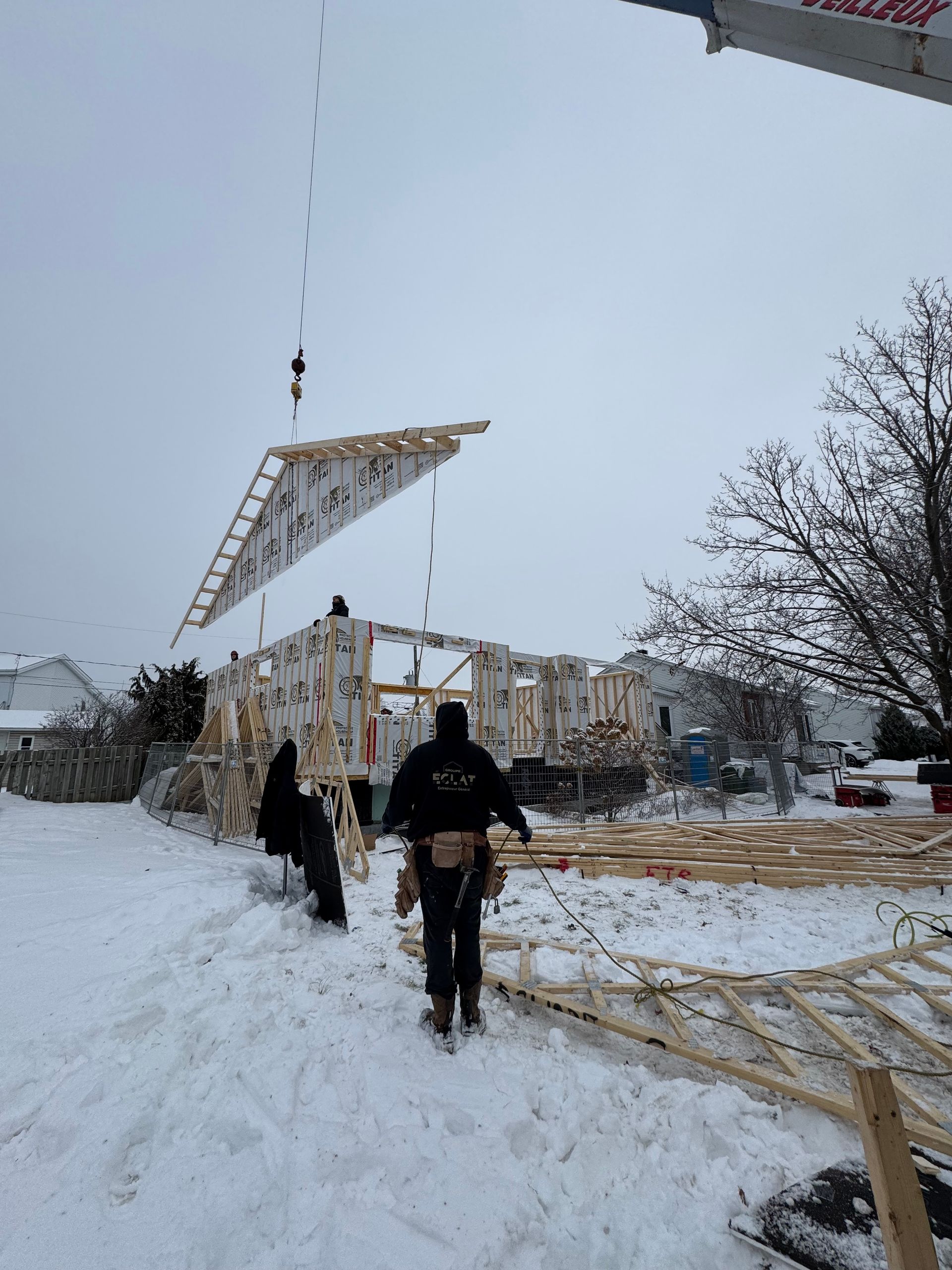 Une grue soulève un morceau de bois dans la neige