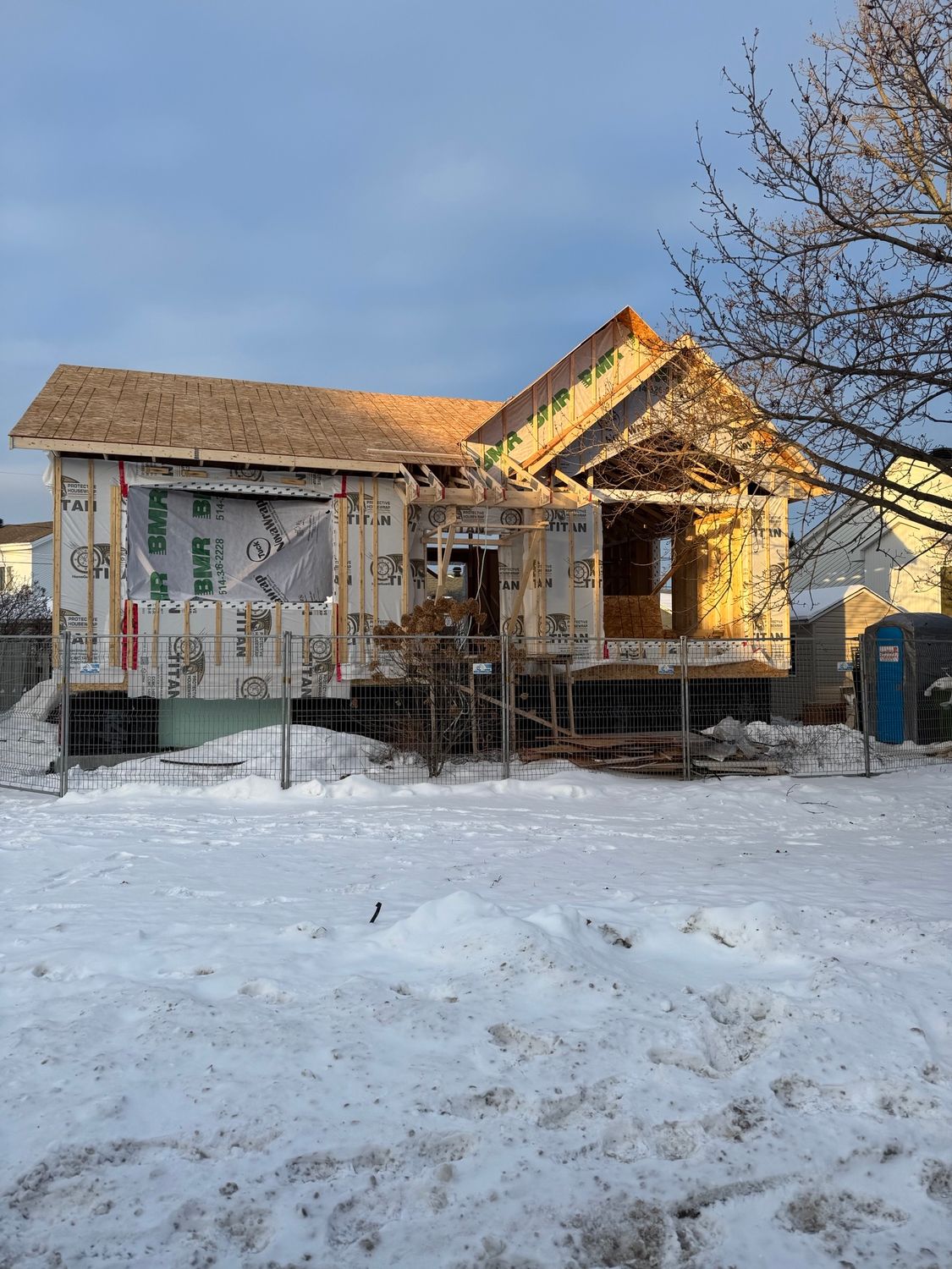 Une maison est en construction dans la neige dans une cour enneigée.