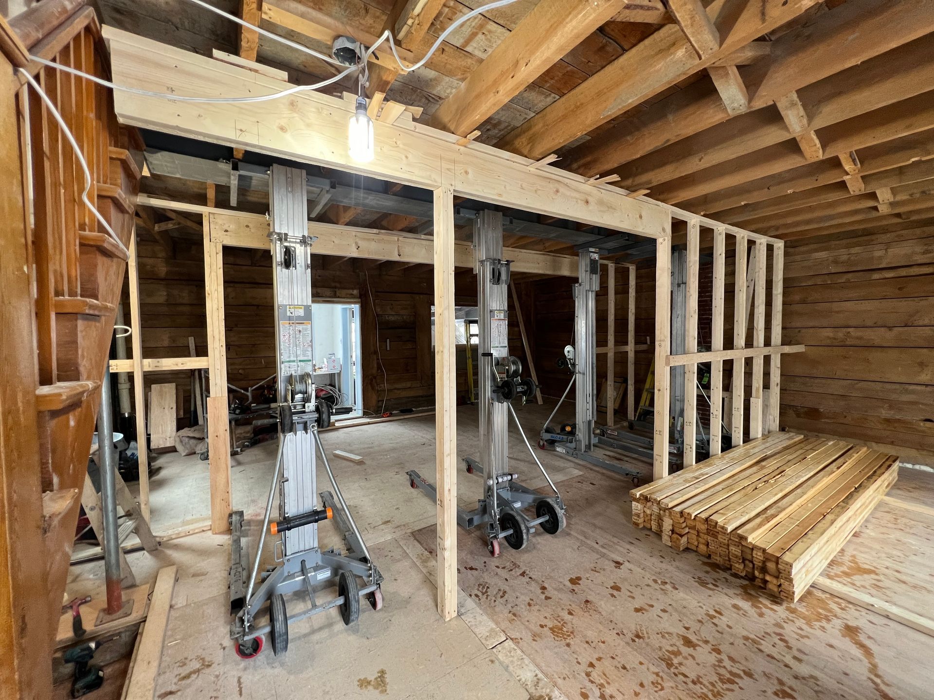 Une pièce en construction avec poutres et escaliers en bois.