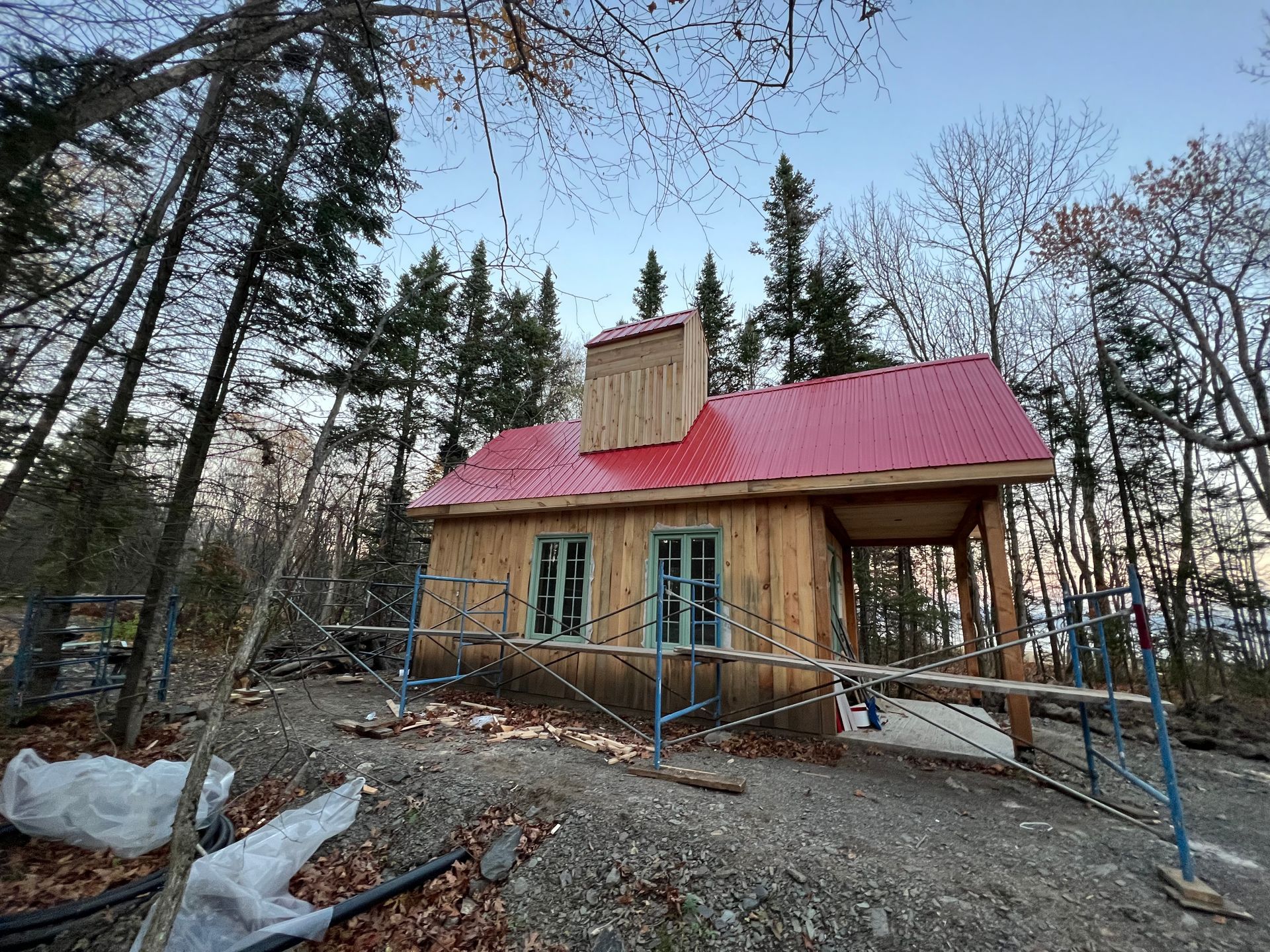 Une petite maison en bois avec un toit rouge est en construction dans les bois.
