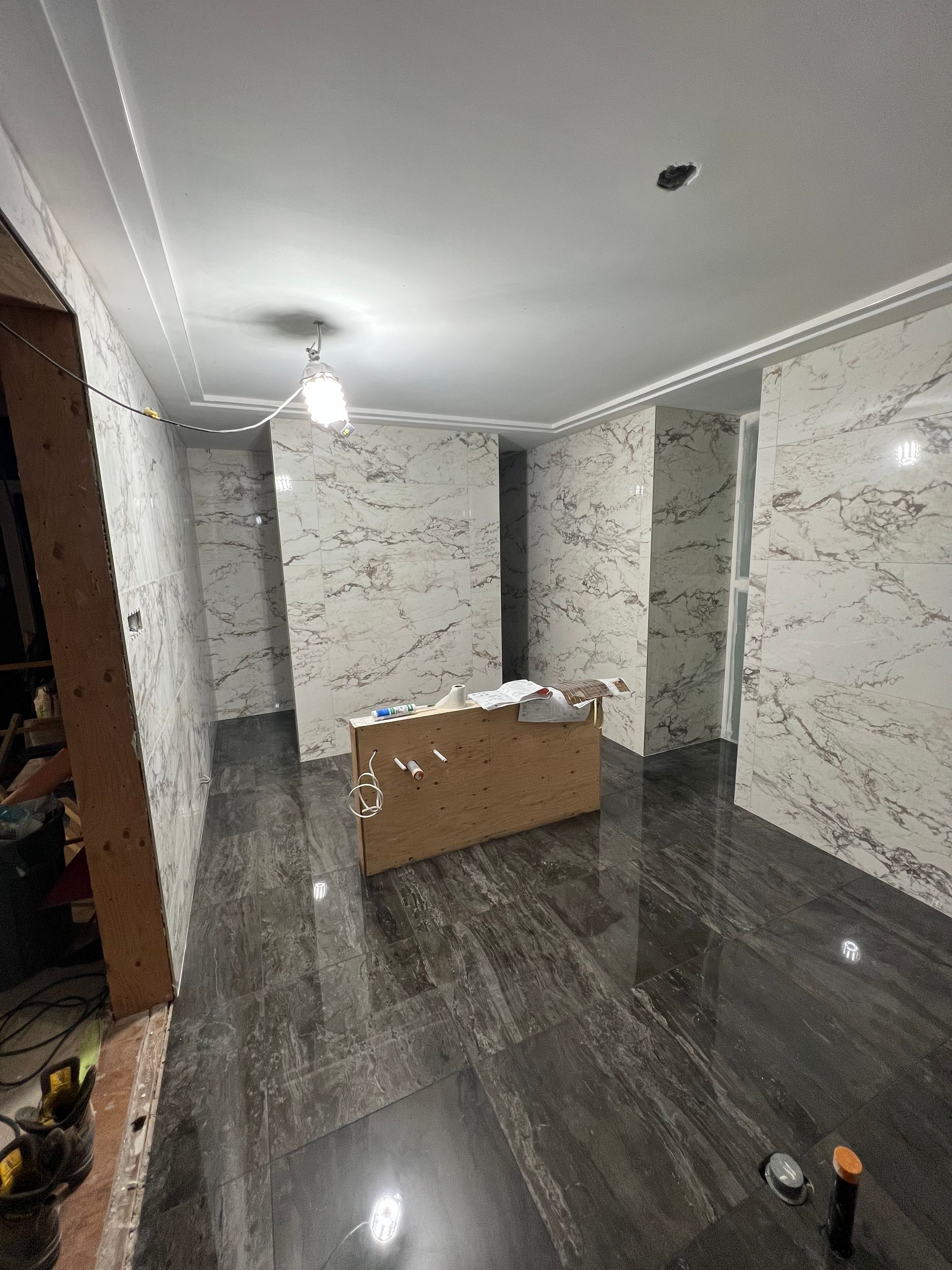 Une pièce avec des murs en marbre et une boîte en bois au sol.