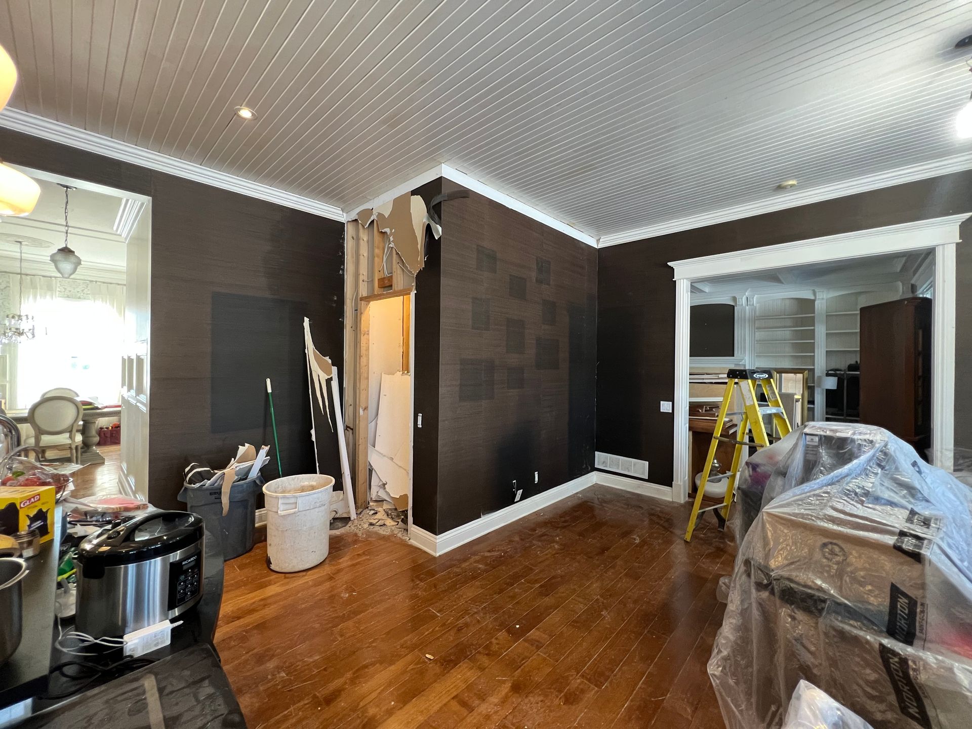 Un salon aux murs marron et au parquet est en cours de rénovation.