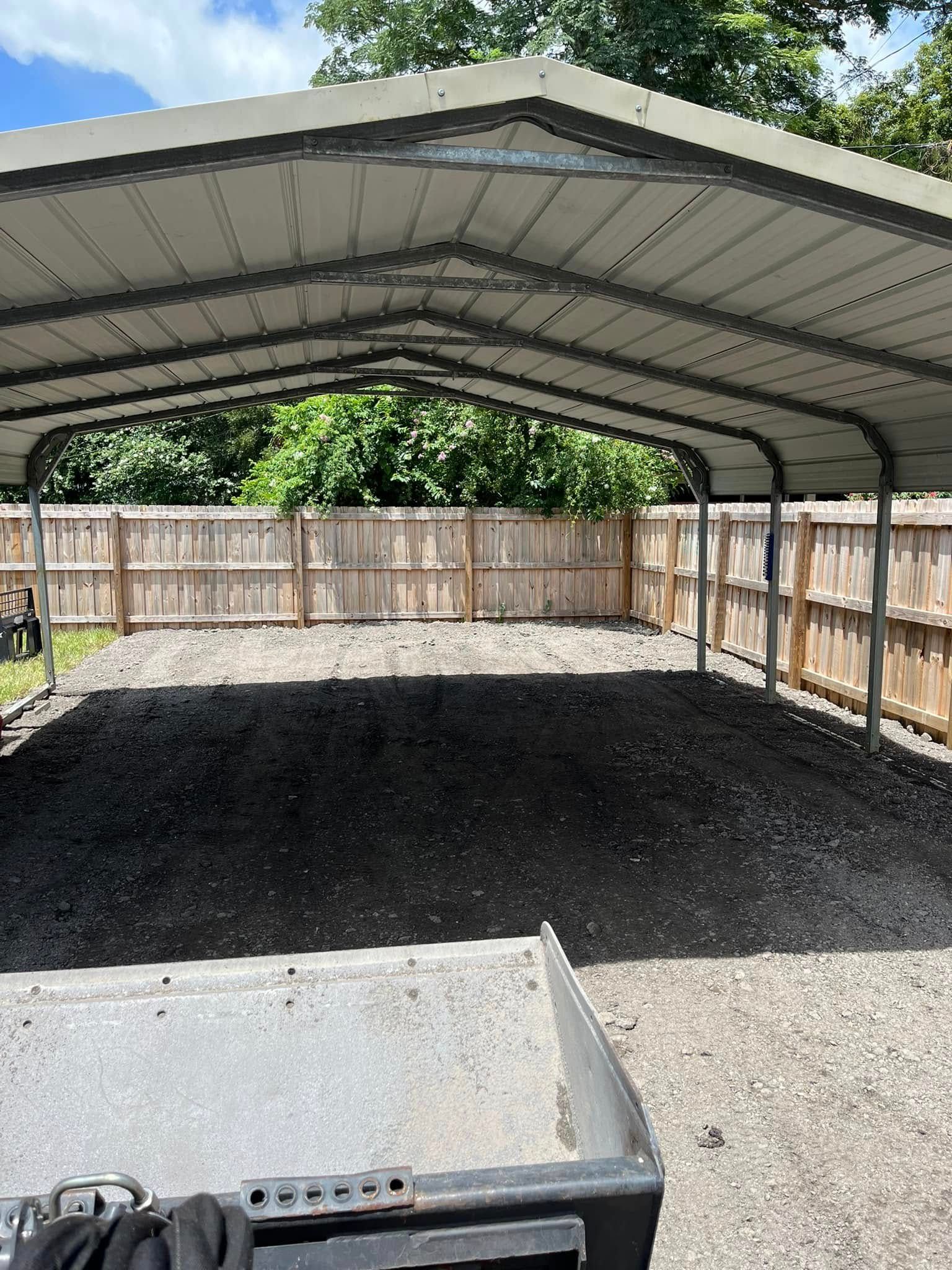 Metal carport over gravel; a wooden fence is in the background.