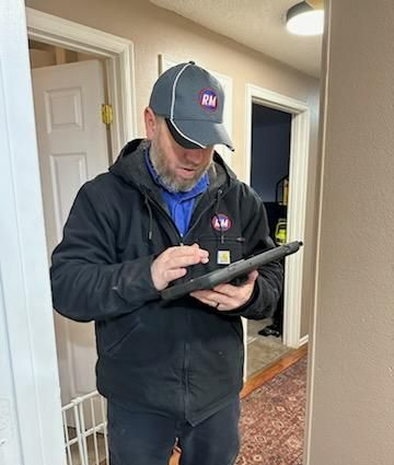Man in jacket and cap using tablet in hallway.