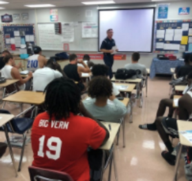 students in classroom looking at teacher in front of room
