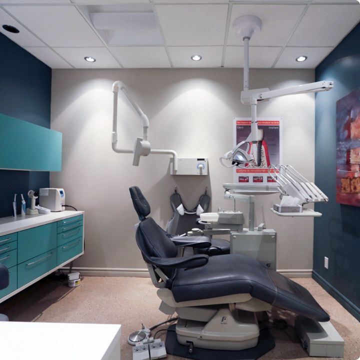 Un cabinet dentaire avec un fauteuil dentaire et un tableau au mur