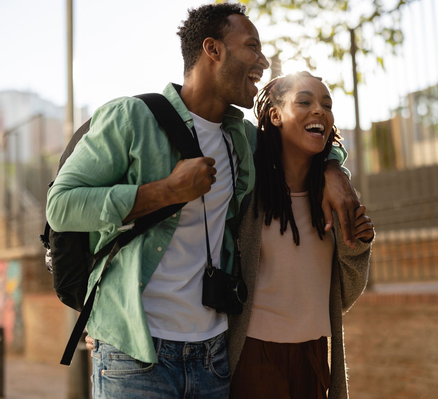 A man and a woman are walking down the street and laughing.