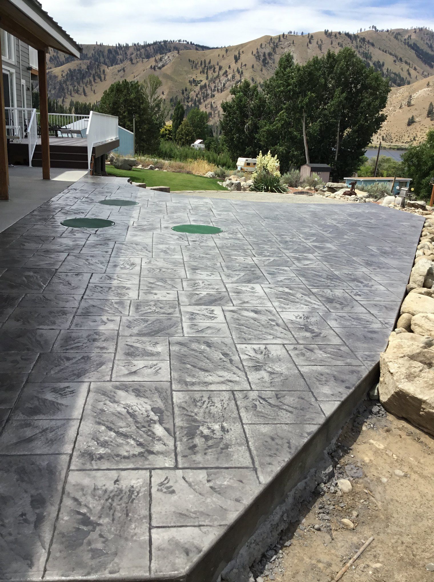 A concrete walkway leading to a house with mountains in the background.