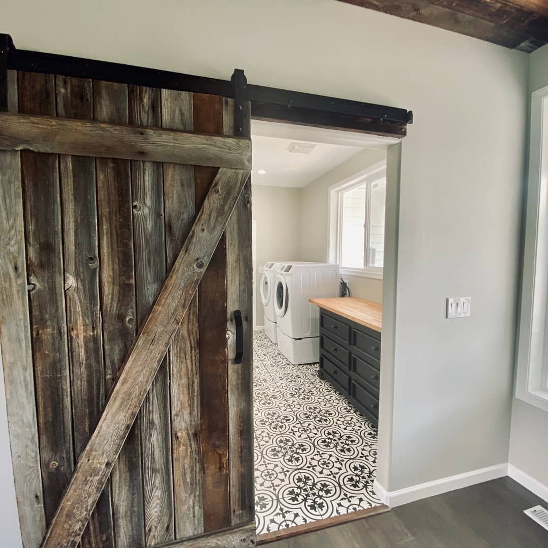 A sliding barn door leads to a laundry room with a washer and dryer.