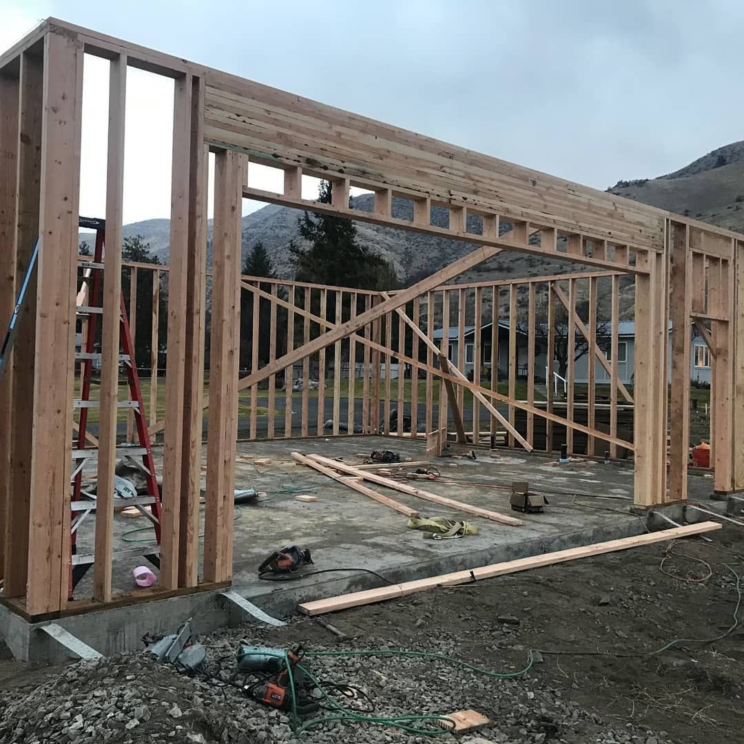 A large wooden structure is being built in the middle of a dirt field.