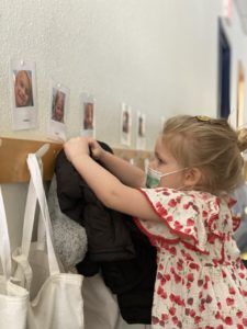 A child hanging up her belongings in the receiving area.