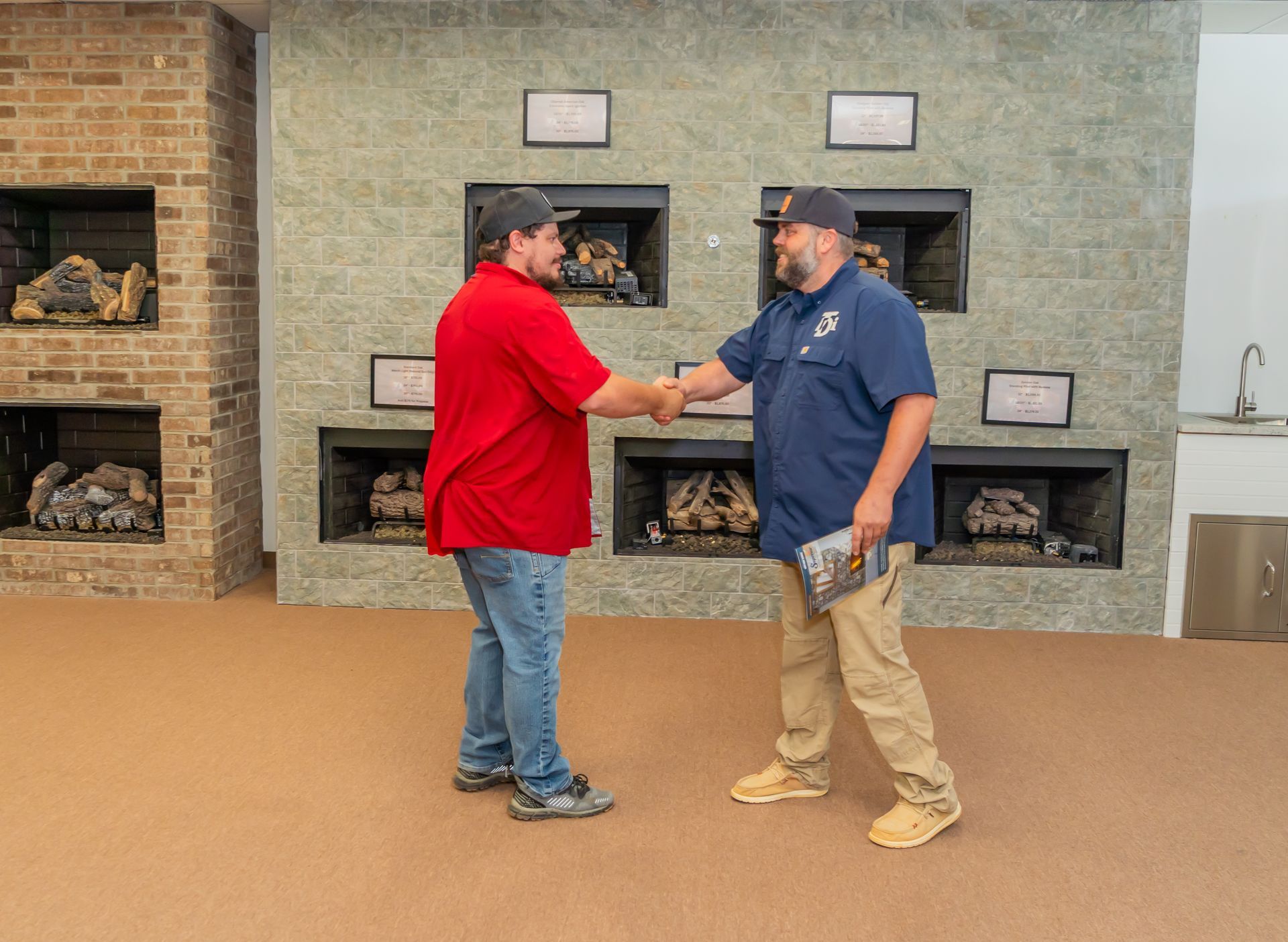 Two men shaking hands in front of fireplace displays; one wears red, the other blue.
