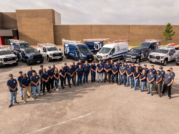 Group of uniformed employees posing with emergency vehicles in a parking lot.