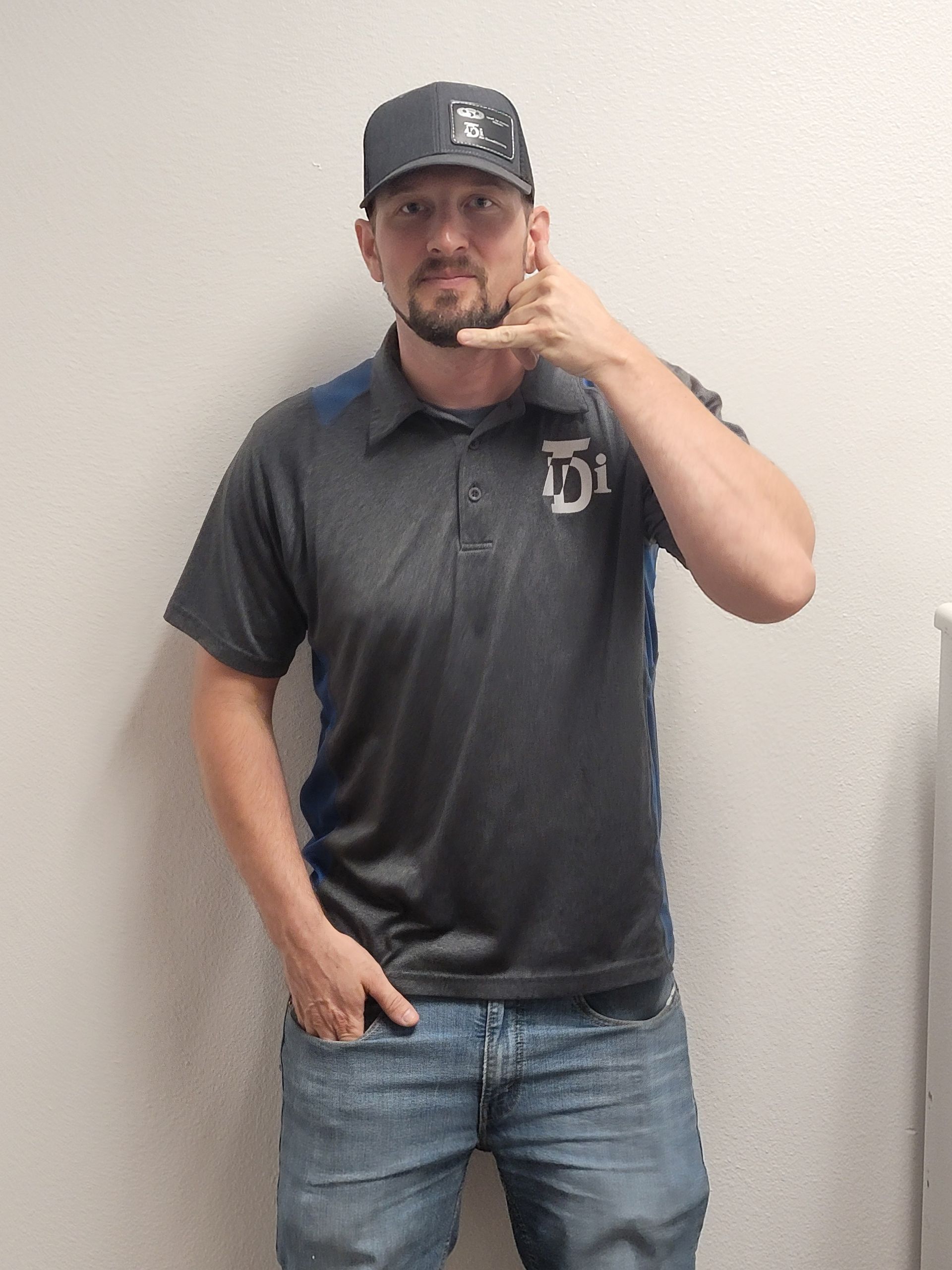 Man in a gray shirt and hat making a 