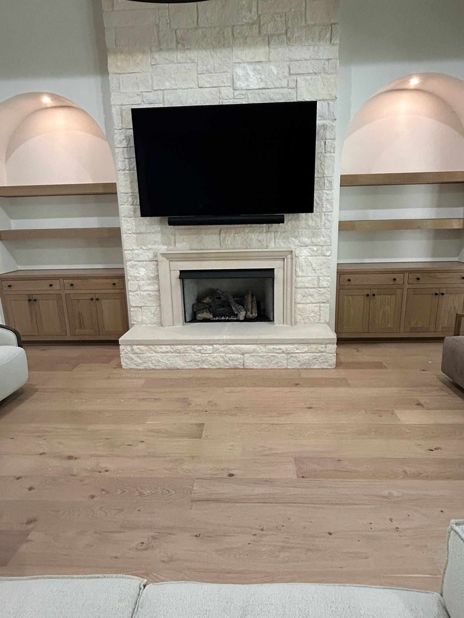 Fireplace with mounted TV, flanked by built-in shelves and cabinets. Light wood floors.