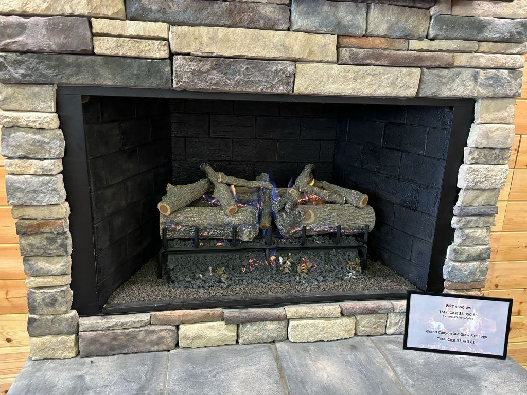 Fireplace with stone surround, logs, and flames.