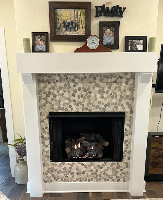 Fireplace with white mantel, stone tile surround, and family photos.