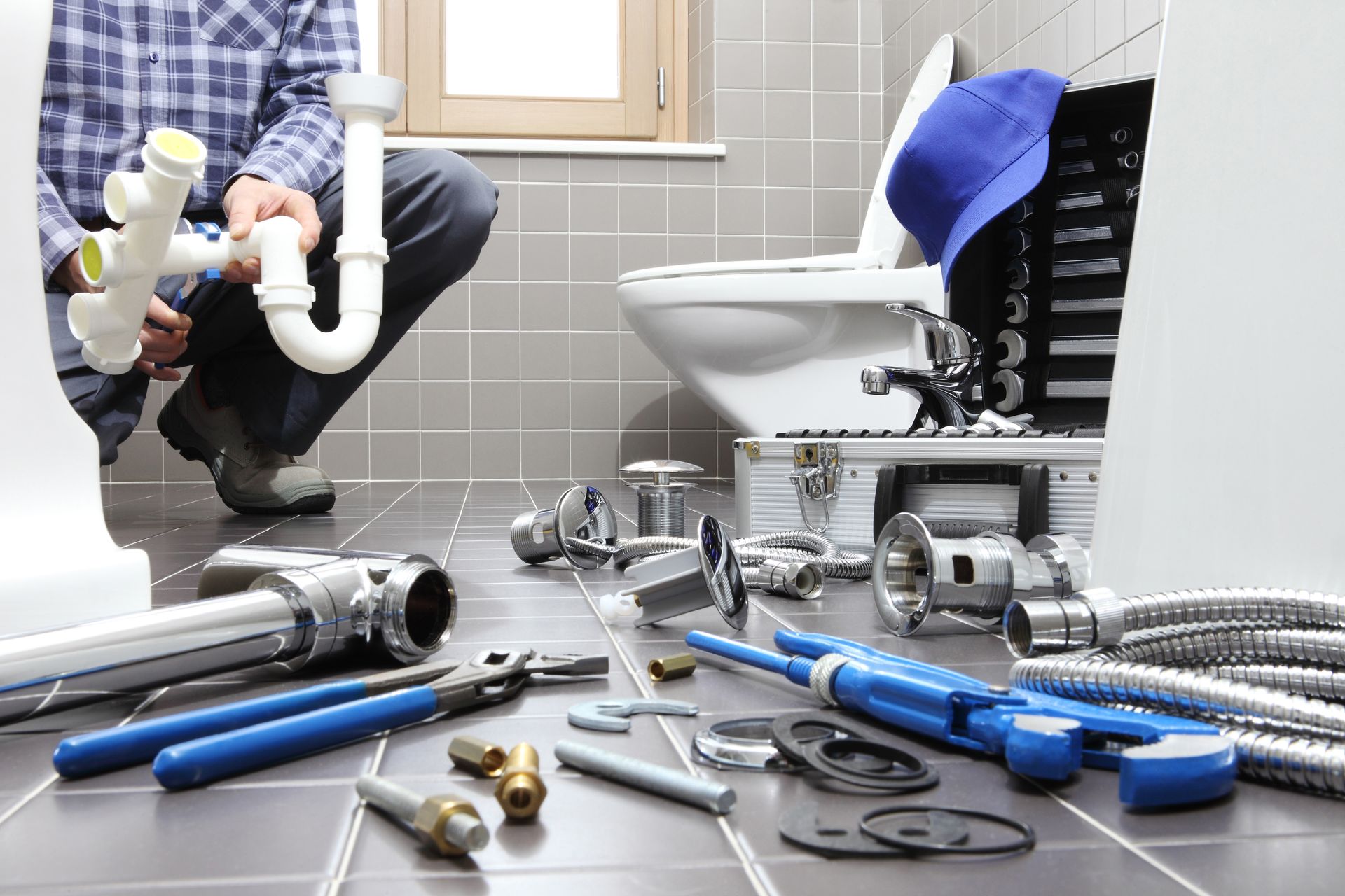 Plumber in bathroom, inspecting pipes and tools near a toilet.
