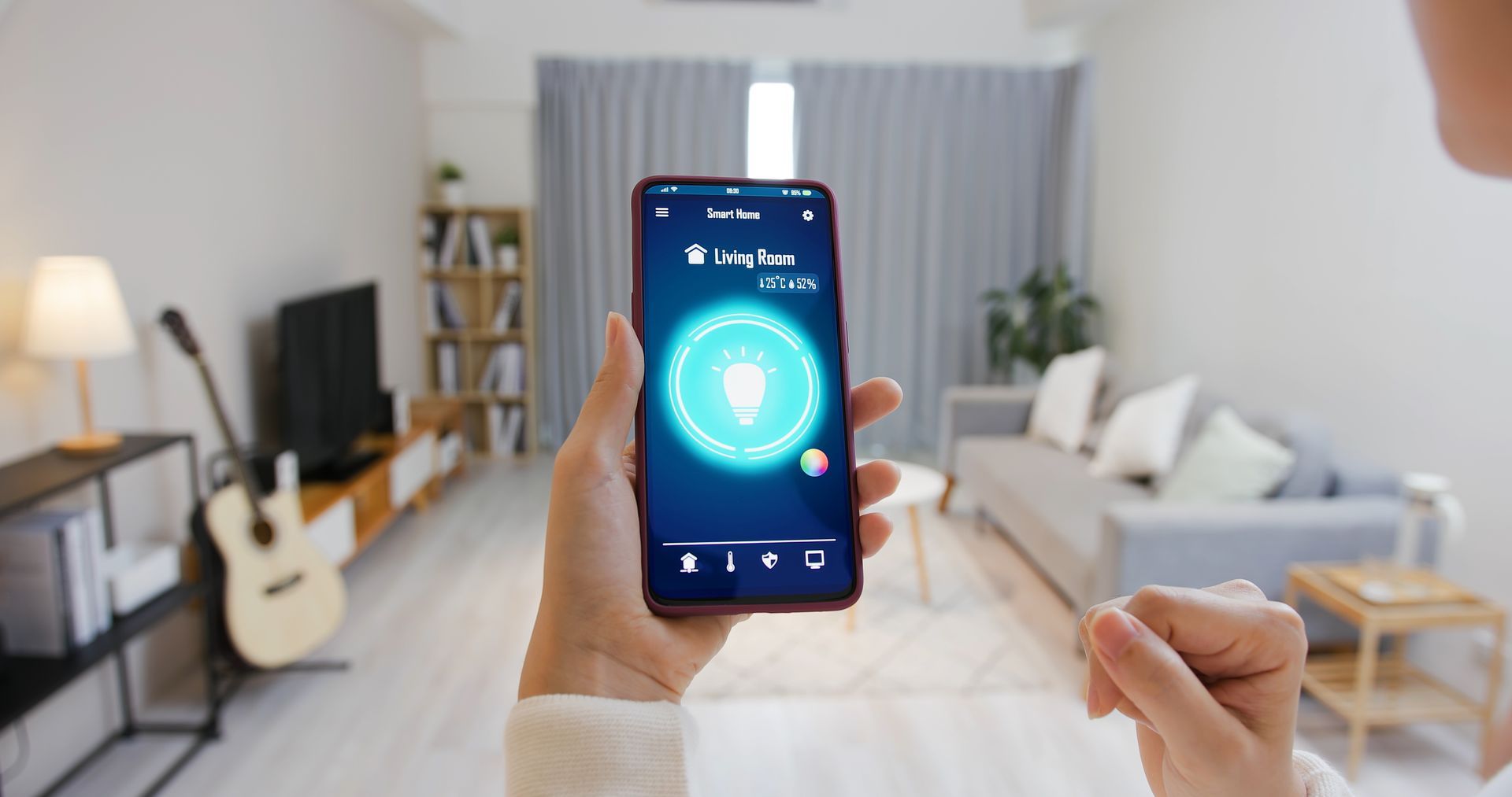 Person holding a smartphone controlling smart home lighting in a living room.