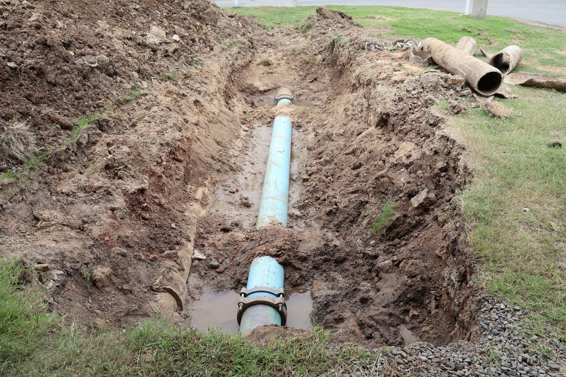 Open trench with a blue and gray water pipe.