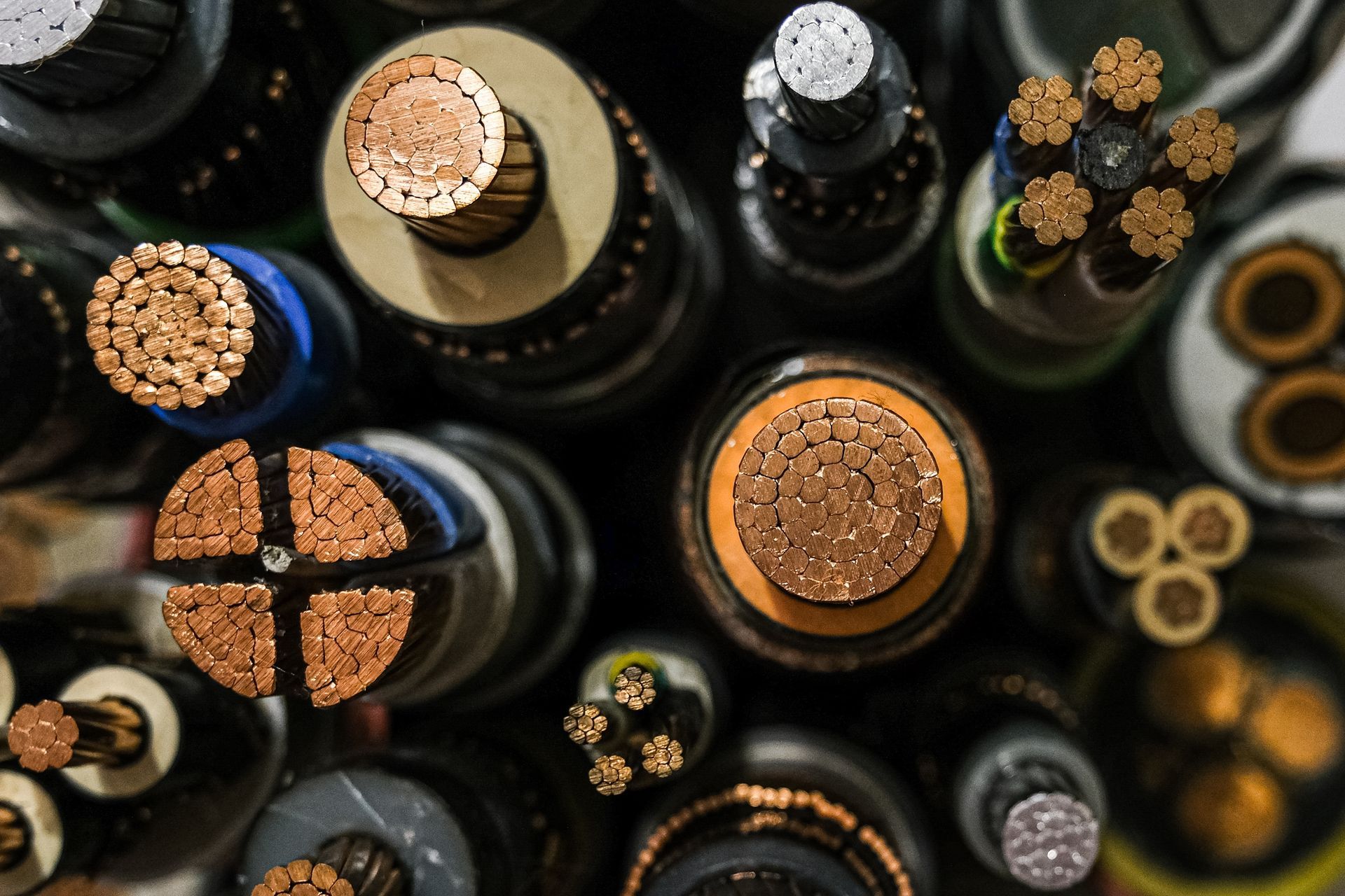 Overhead view of several cut power cables, showing copper conductors and insulation of various colors.