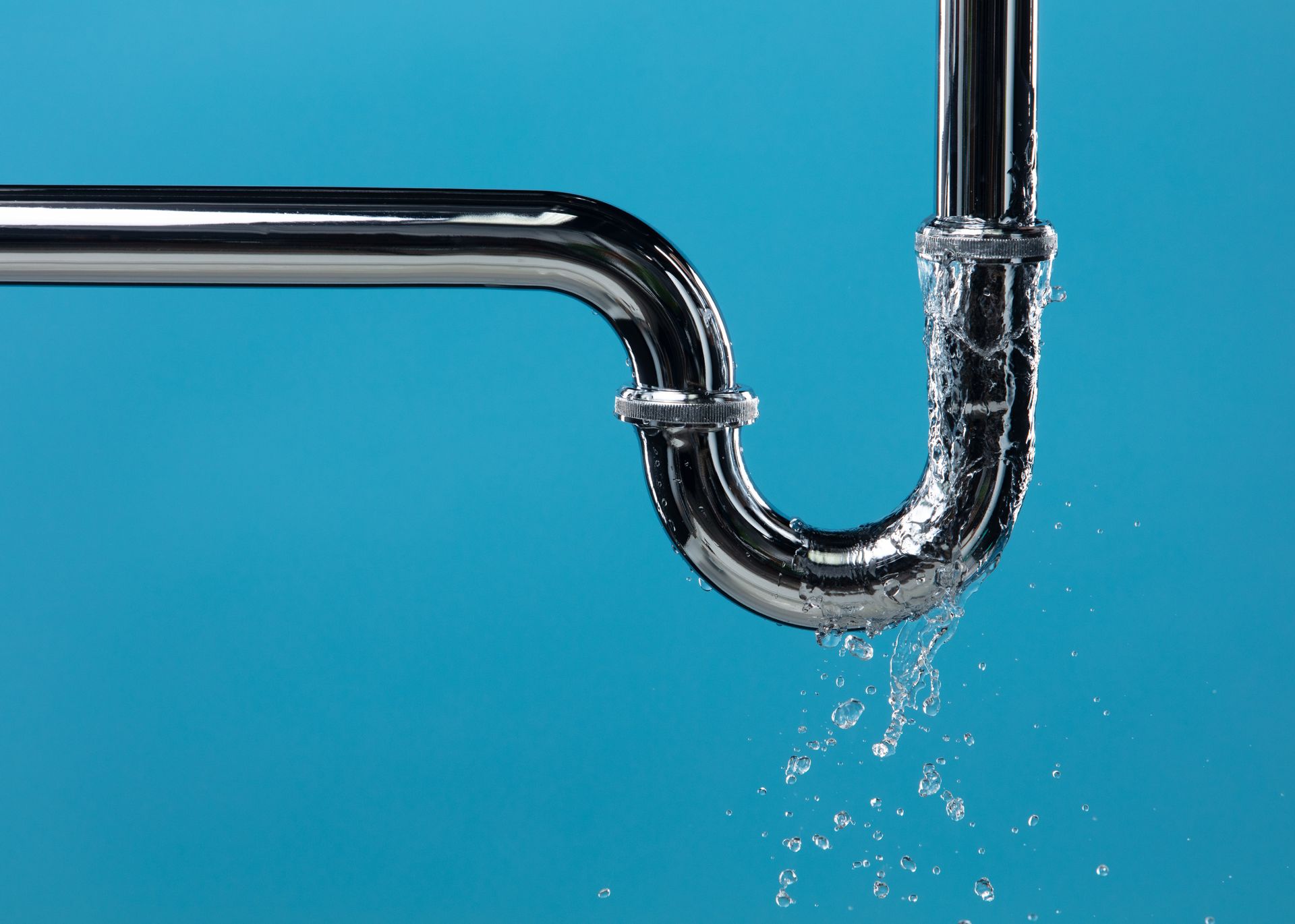 Leaking silver plumbing pipe against a blue background. Water droplets falling.