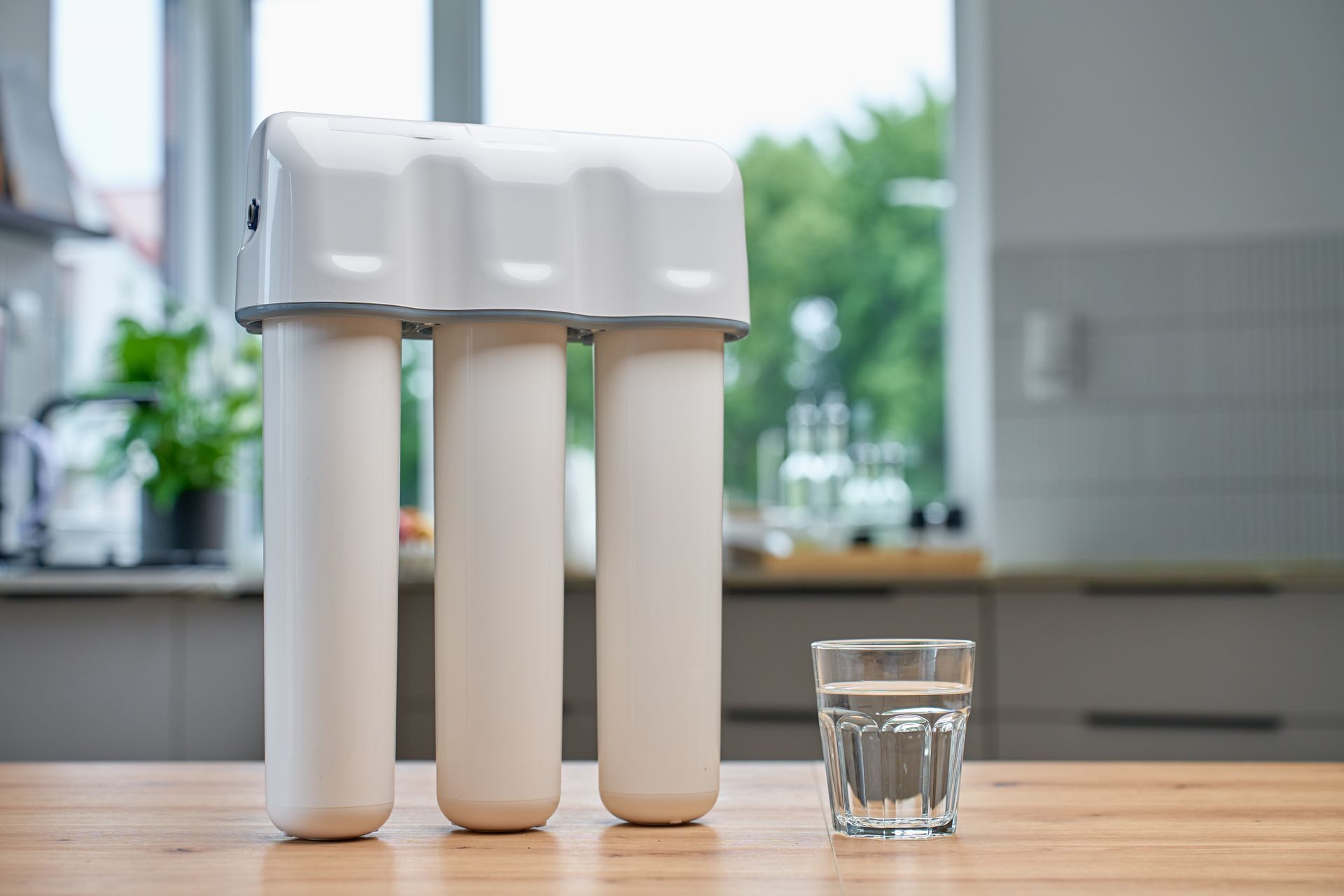Water filter system with a glass of water on a kitchen counter.