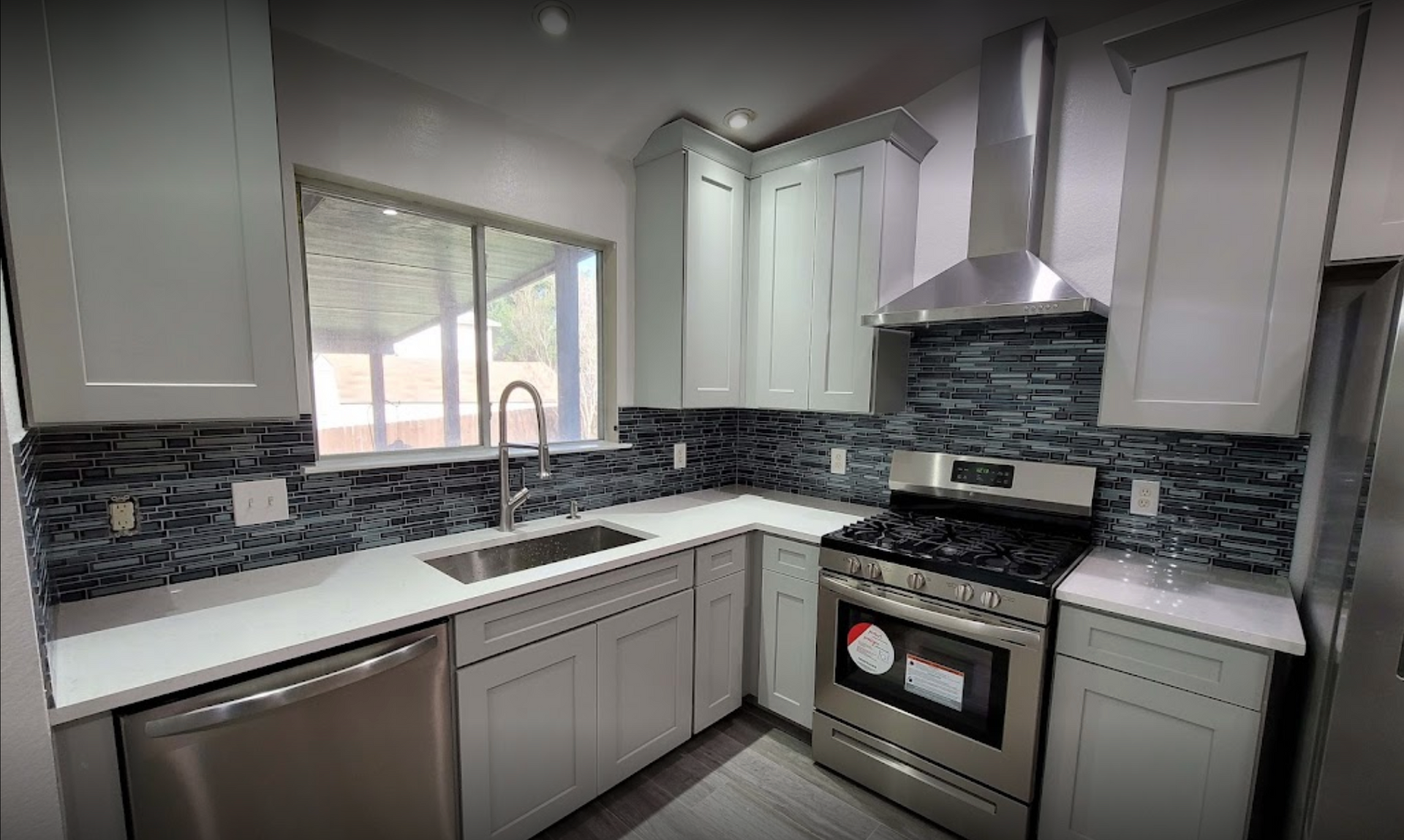 A kitchen remodel with new white cabinets, stainless steel appliances, a sink, and a stove.