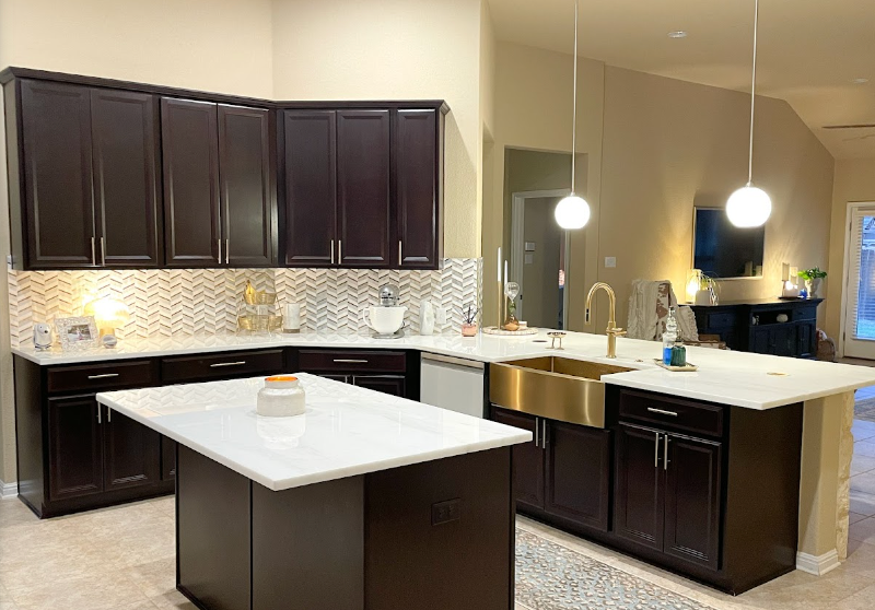 A newly remodeled kitchen with brown cabinets, white countertops, a sink, and a large island.