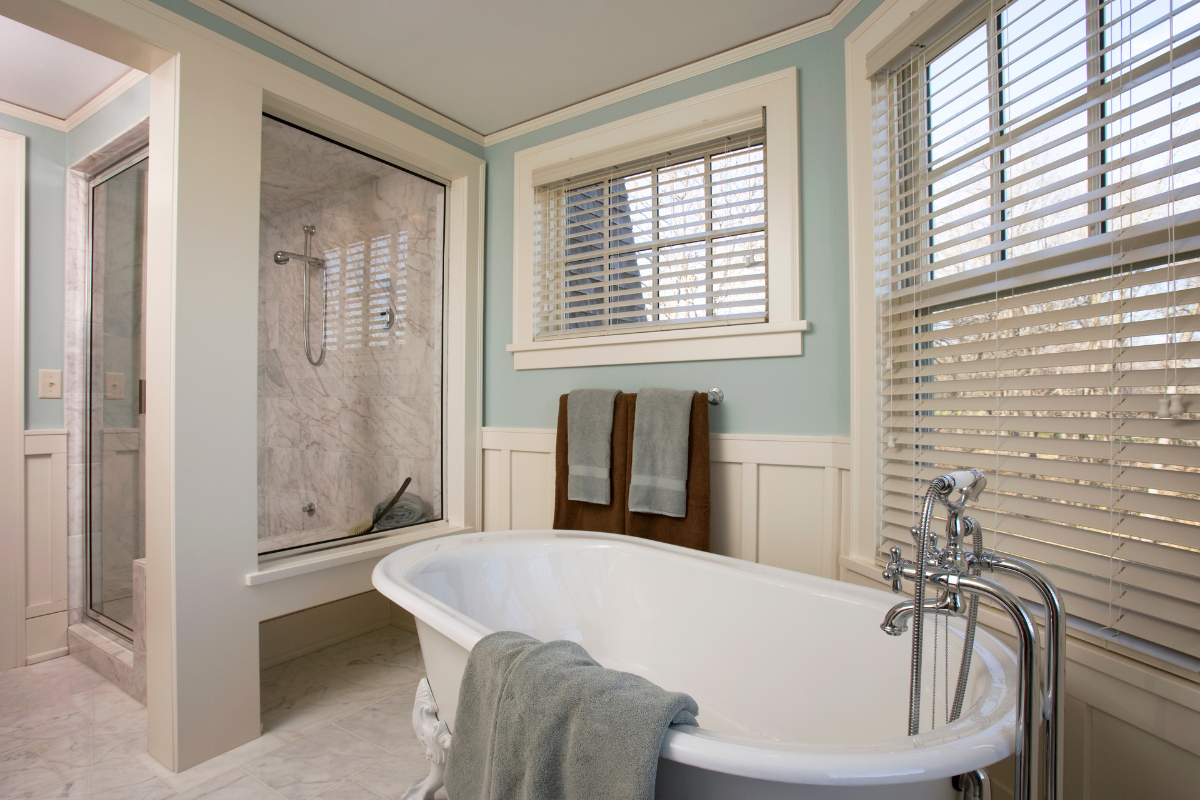 A bathroom with a tub , shower and window