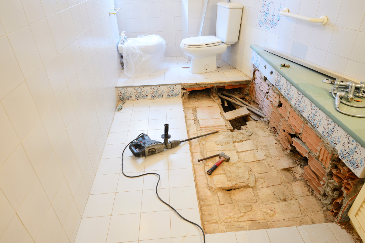 A bathroom under construction with a toilet and a drill on the floor.