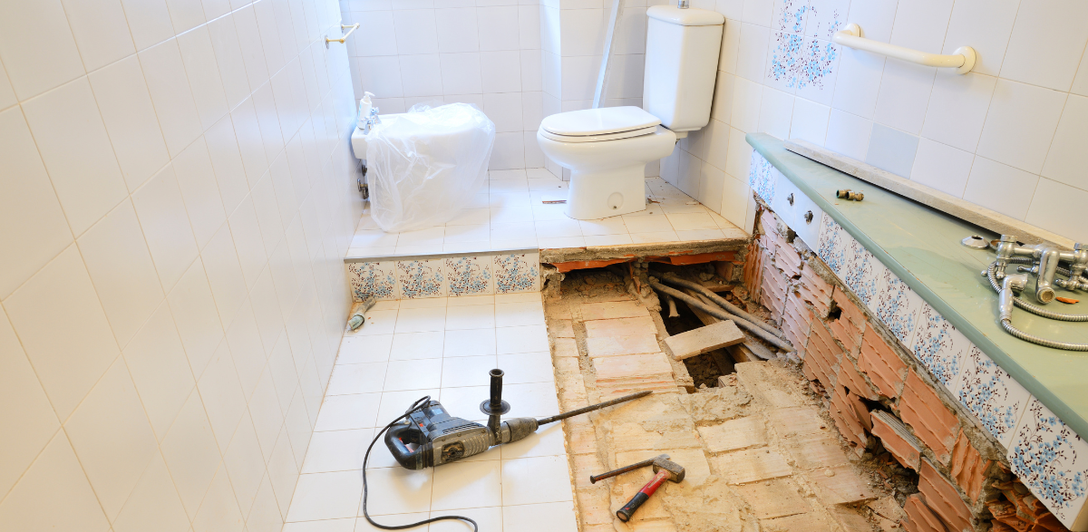 A bathroom under construction with a toilet and a drill on the floor.