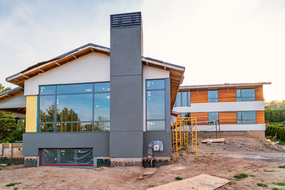 A custom home is being built in the middle of a dirt field.