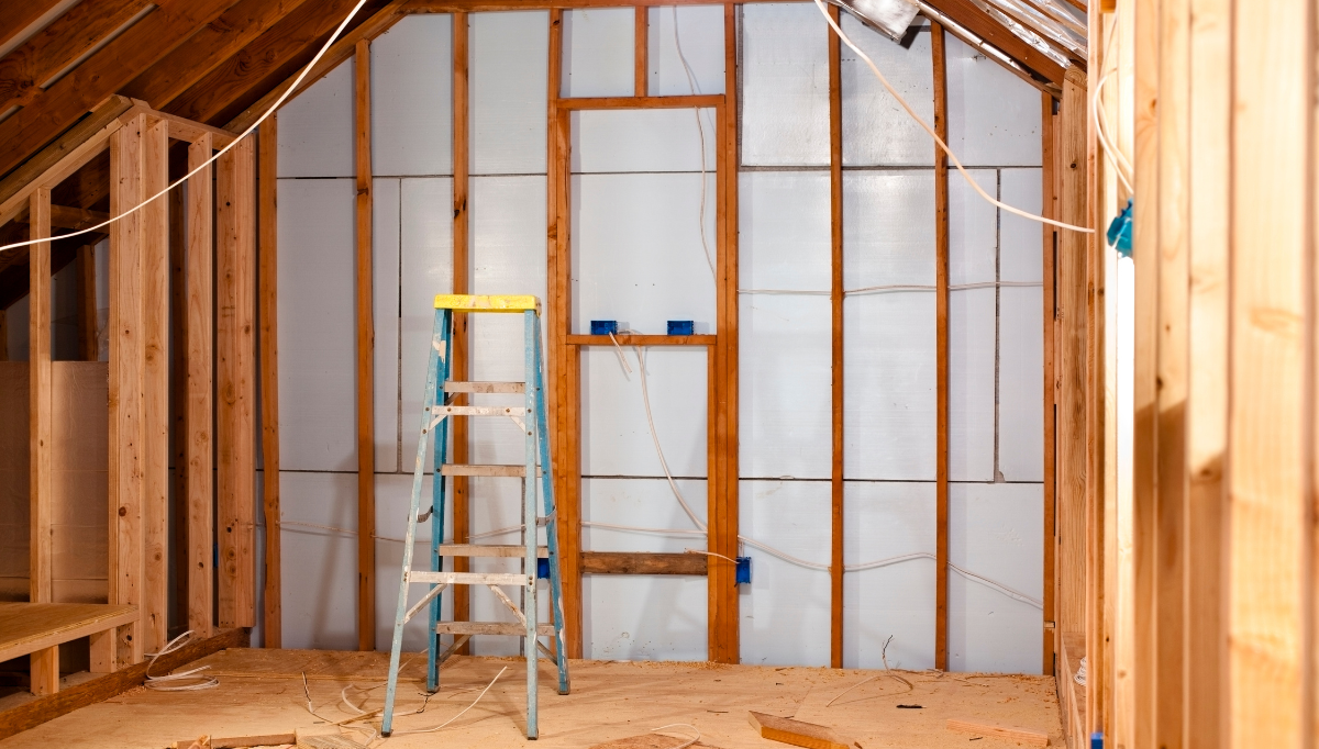 A ladder is sitting in the middle of a room under construction.