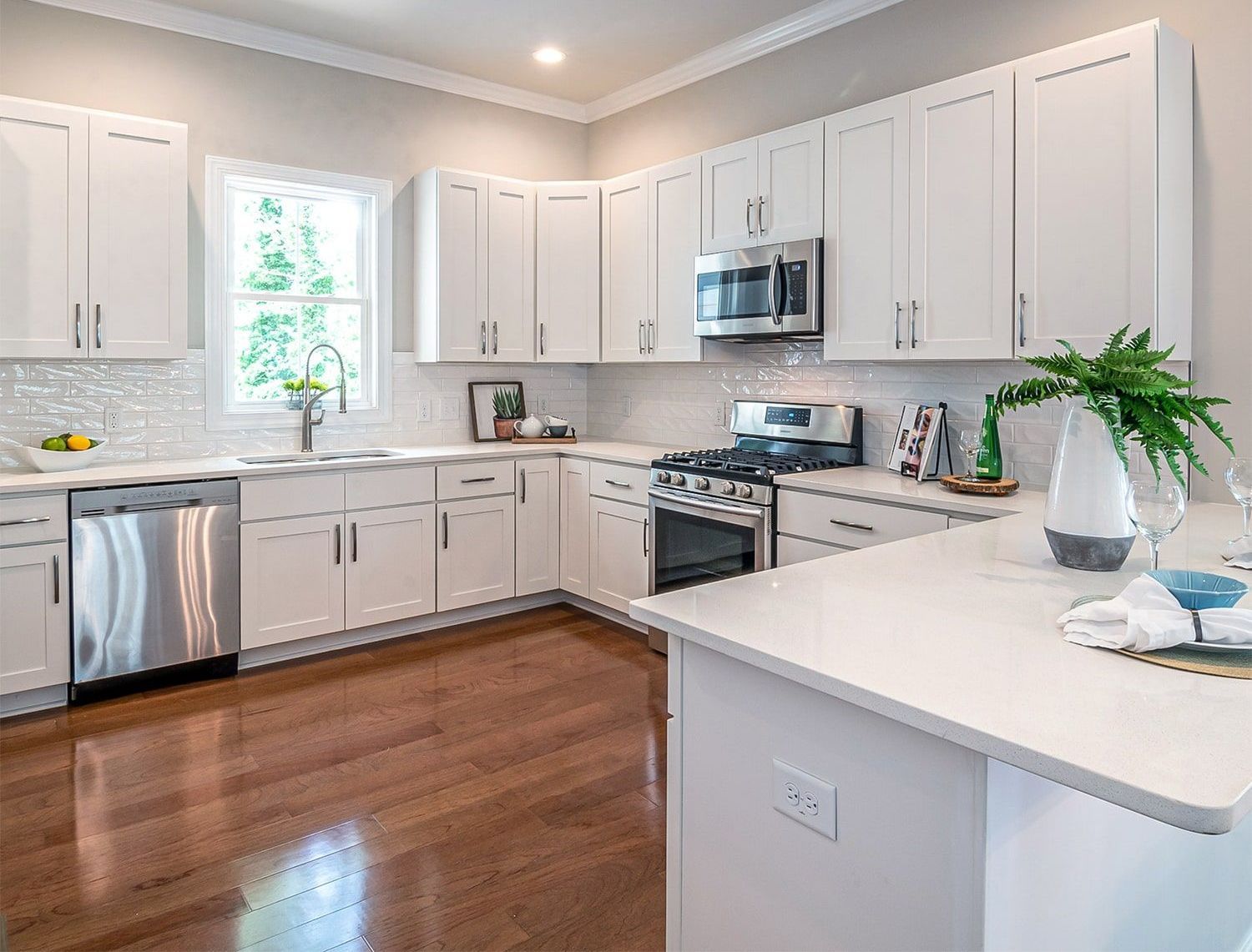 A kitchen with white cabinets , stainless steel appliances , and hardwood floors.